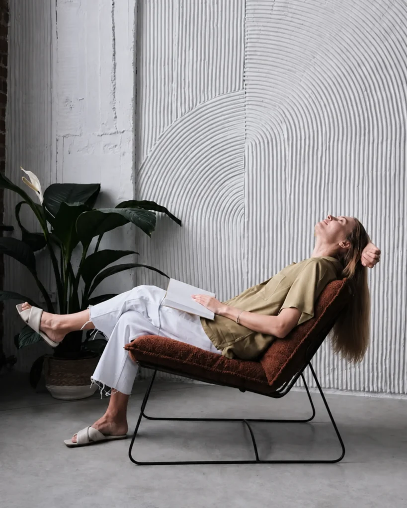Woman relaxing in a calm, softly lit room, reflecting the supportive space at Exhale TRE